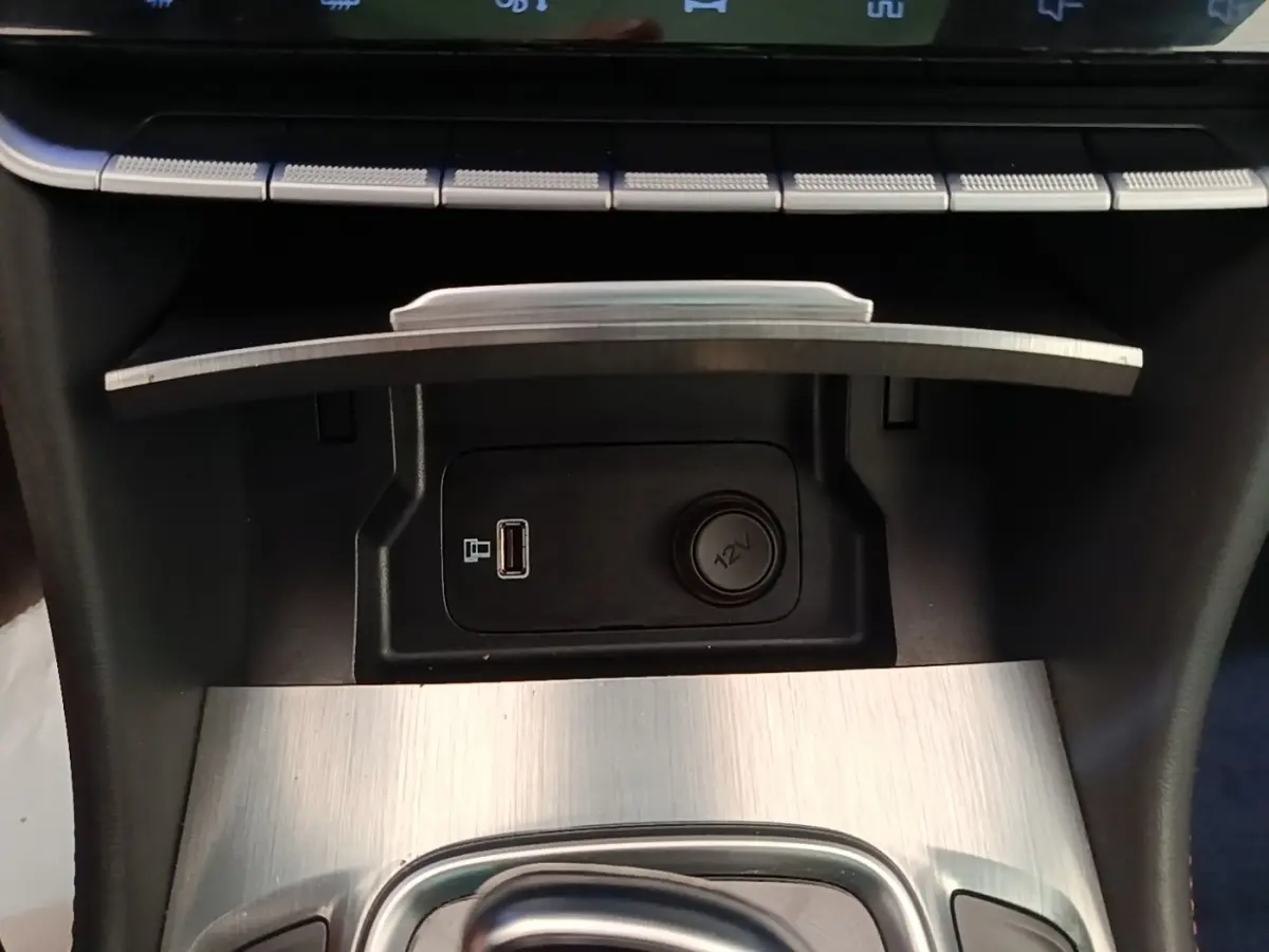 Gros plan sur la console centrale du MG Motor EHS 2023, montrant prise USB, prise 12V et finition aluminium brossé.