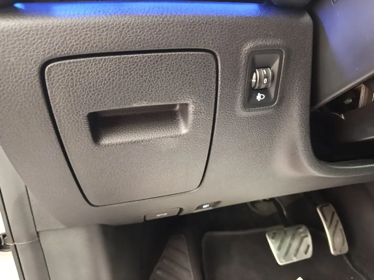 Vue intérieure côté conducteur du MG Motor EHS 2023, montrant le tableau de bord inférieur noir avec commande de réglage des phares.