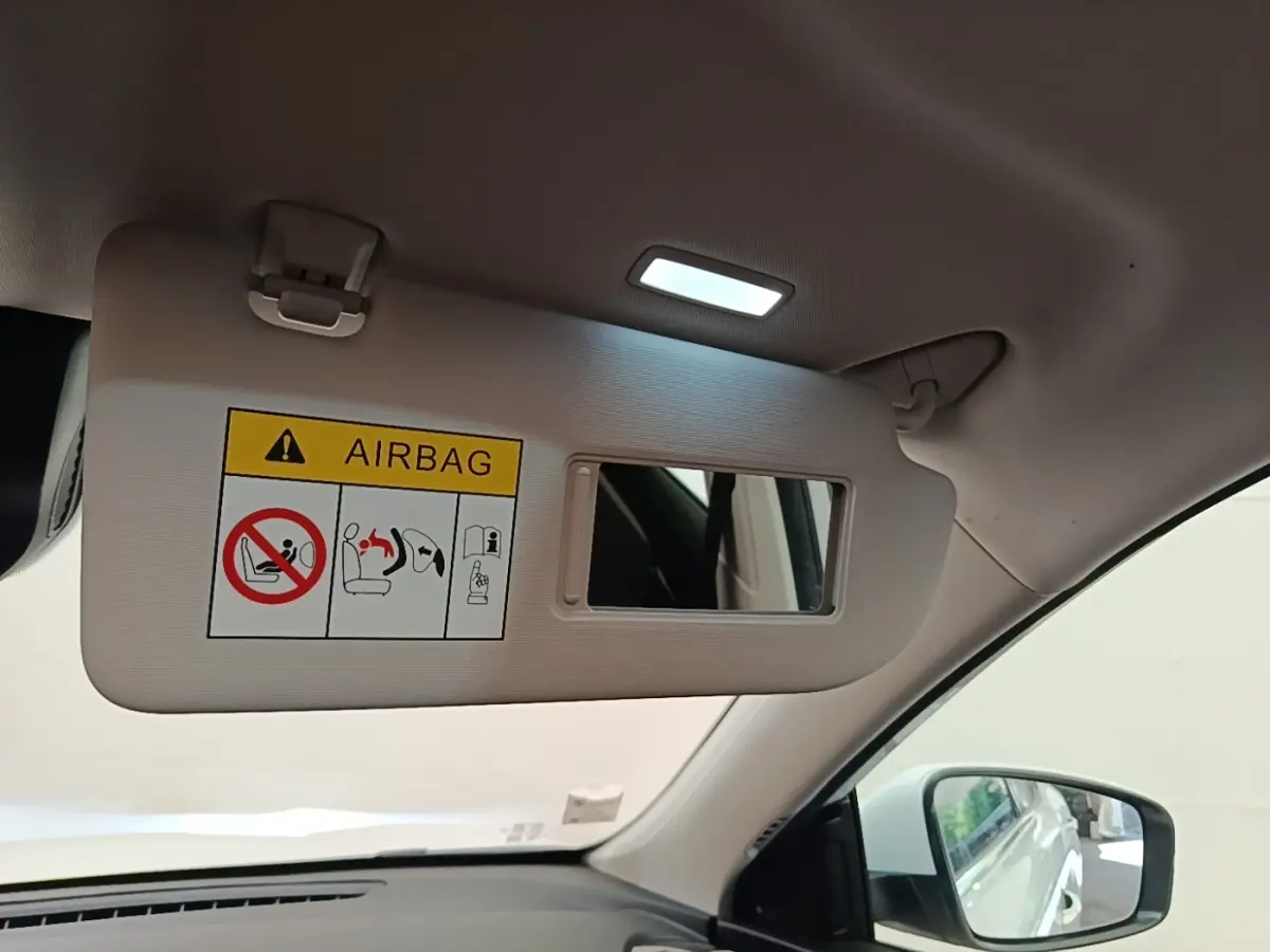 Détail intérieur du pare-soleil côté conducteur avec miroir et avertissement airbag dans un MG Motor EHS blanc.