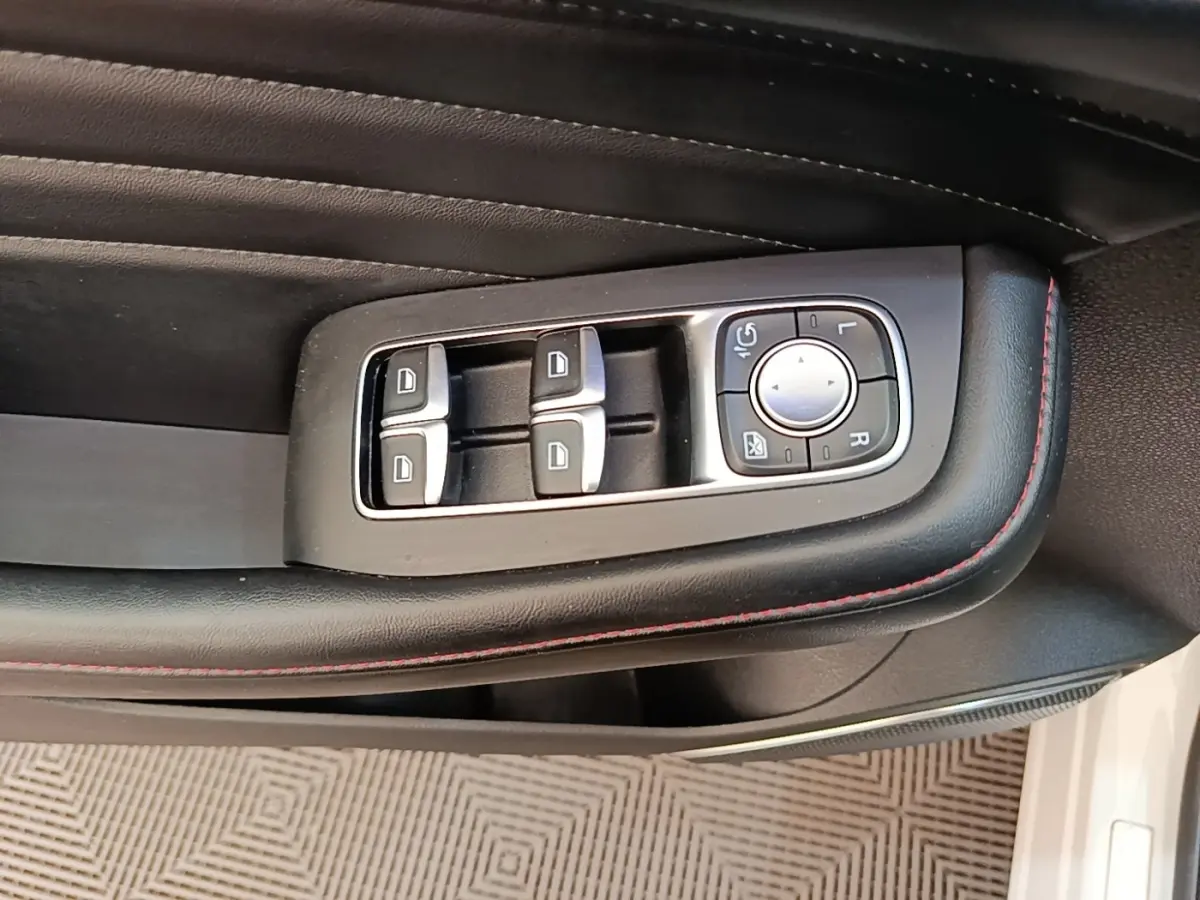 Gros plan sur les commandes des vitres et rétroviseurs côté conducteur du MG Motor EHS blanc 2023.