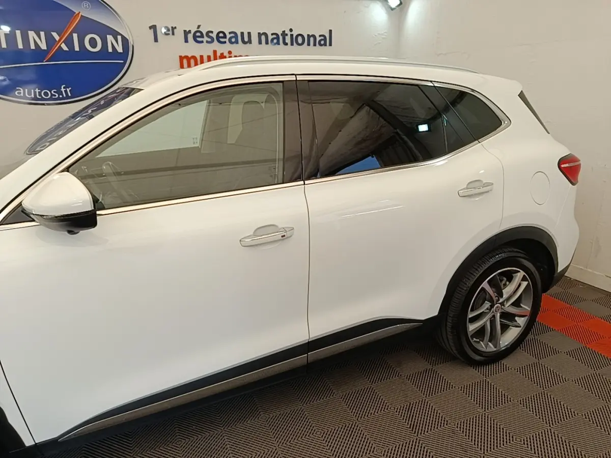Vue latérale droite du MG Motor EHS blanc 2023, soulignant ses jantes alliage et ses vitres teintées.