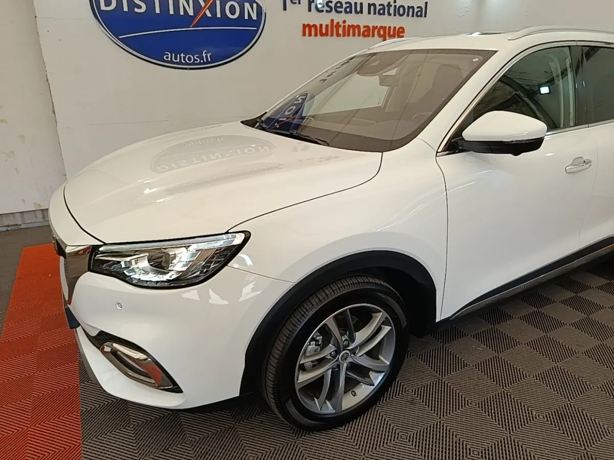 Vue 3/4 avant droit du MG MOTOR EHS blanc, mettant en valeur ses phares LED et jantes alliage modernes.