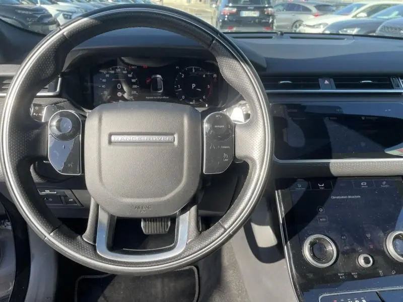 Vue intérieure centrée sur le volant noir du Range Rover Velar 2020, avec tableau de bord numérique et console tactile visible.