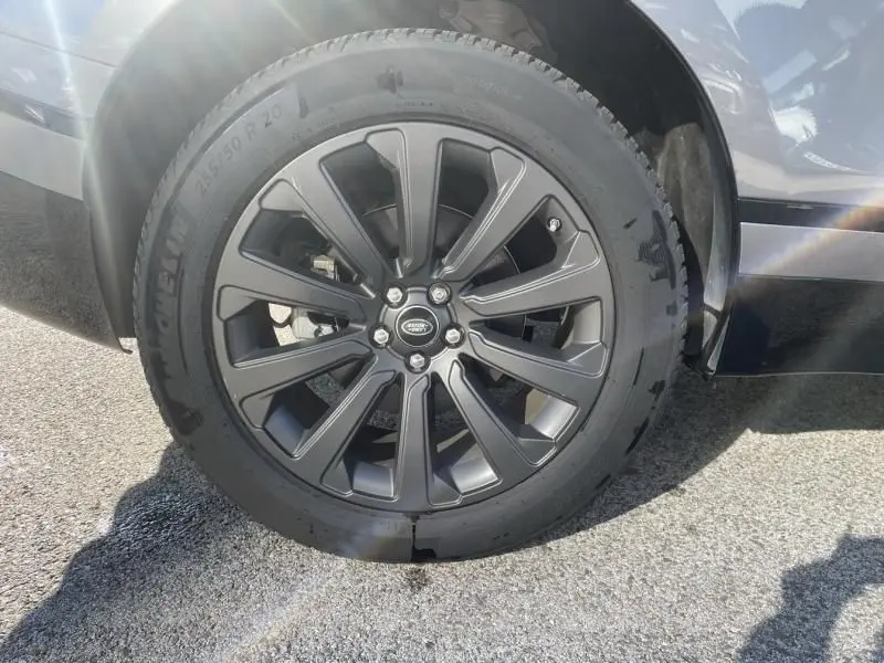 Gros plan sur la jante noire du Range Rover Velar gris métal, mettant en valeur le logo Land Rover central.