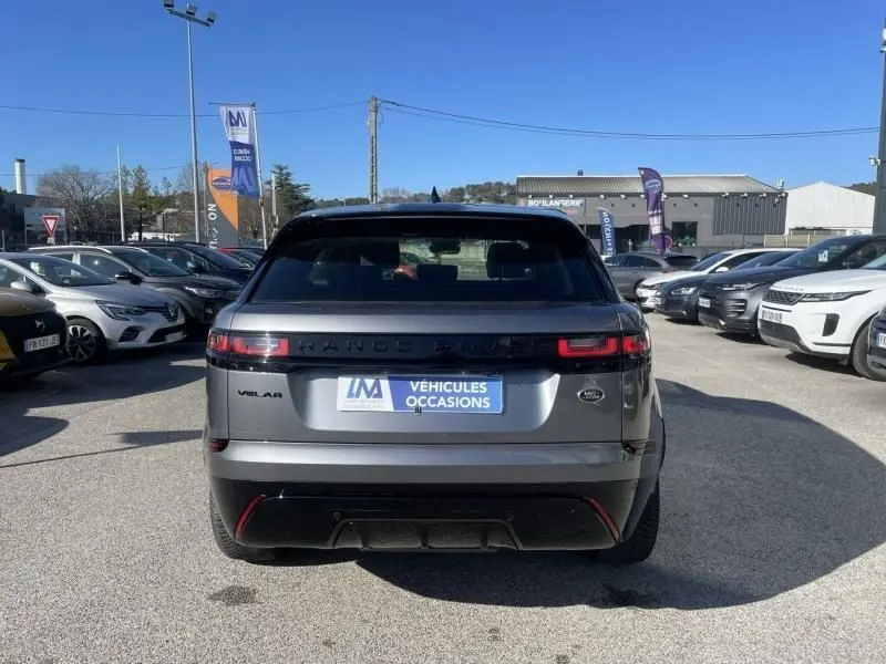 Vue arrière d'un Range Rover Velar gris métal 2020 avec feux LED et badge R-DYNAMIC SE visible sur un parking.