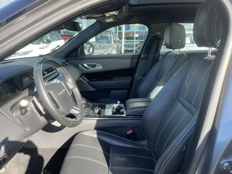 Intérieur du Range Rover Velar 2020 gris métal, vue côté conducteur montrant sièges cuir noirs et tableau de bord moderne.
