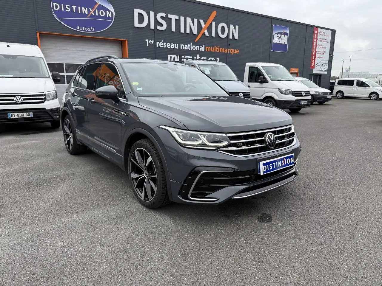 Volkswagen Tiguan 2.0 TDI gris dauphin en 3/4 avant avec jantes alliage 20 pouces et calandre R-Line visible.