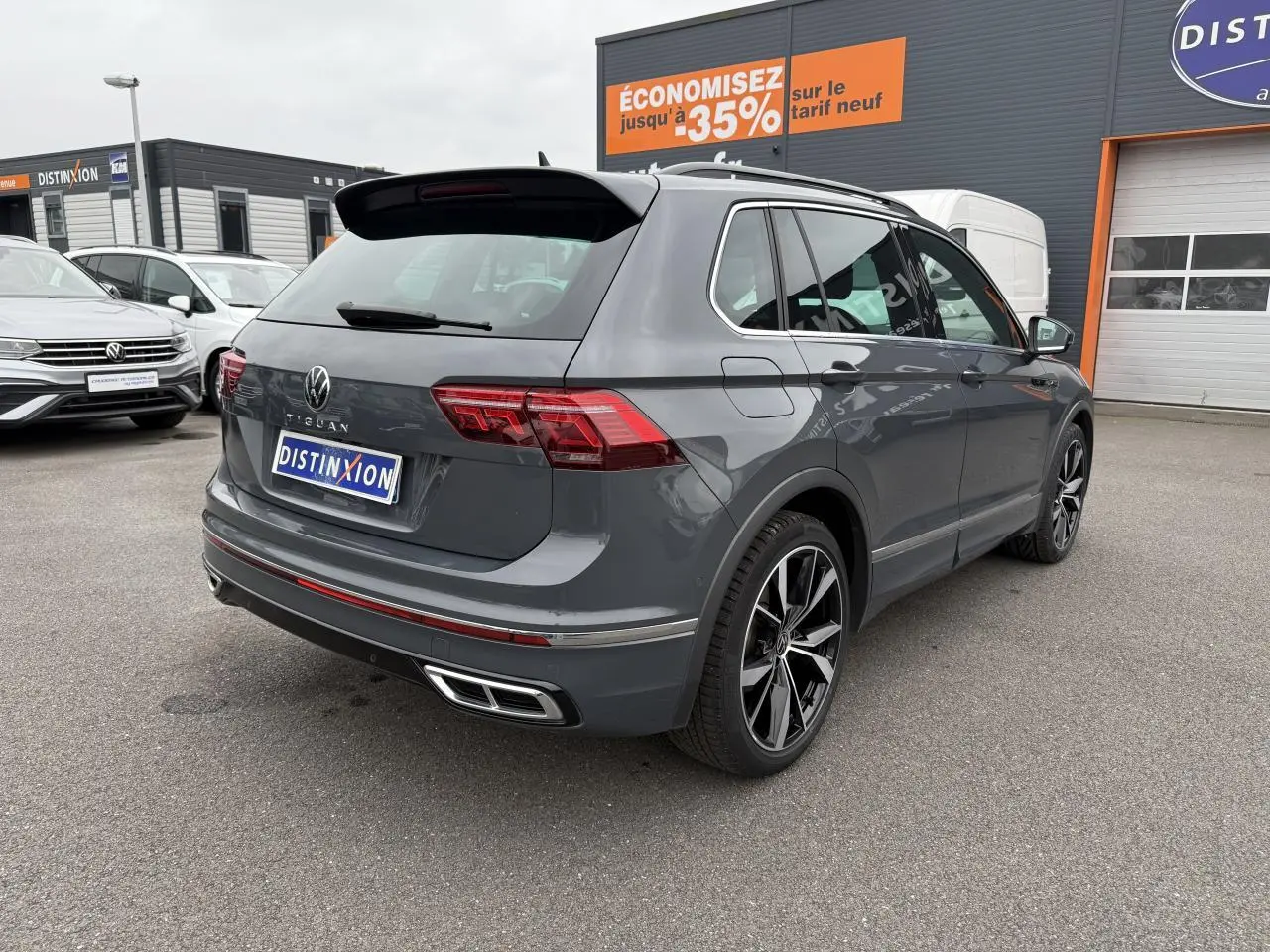 Vue 3/4 arrière droite d'un Volkswagen Tiguan gris dauphin avec jantes alliage 20 pouces et double sortie d'échappement.