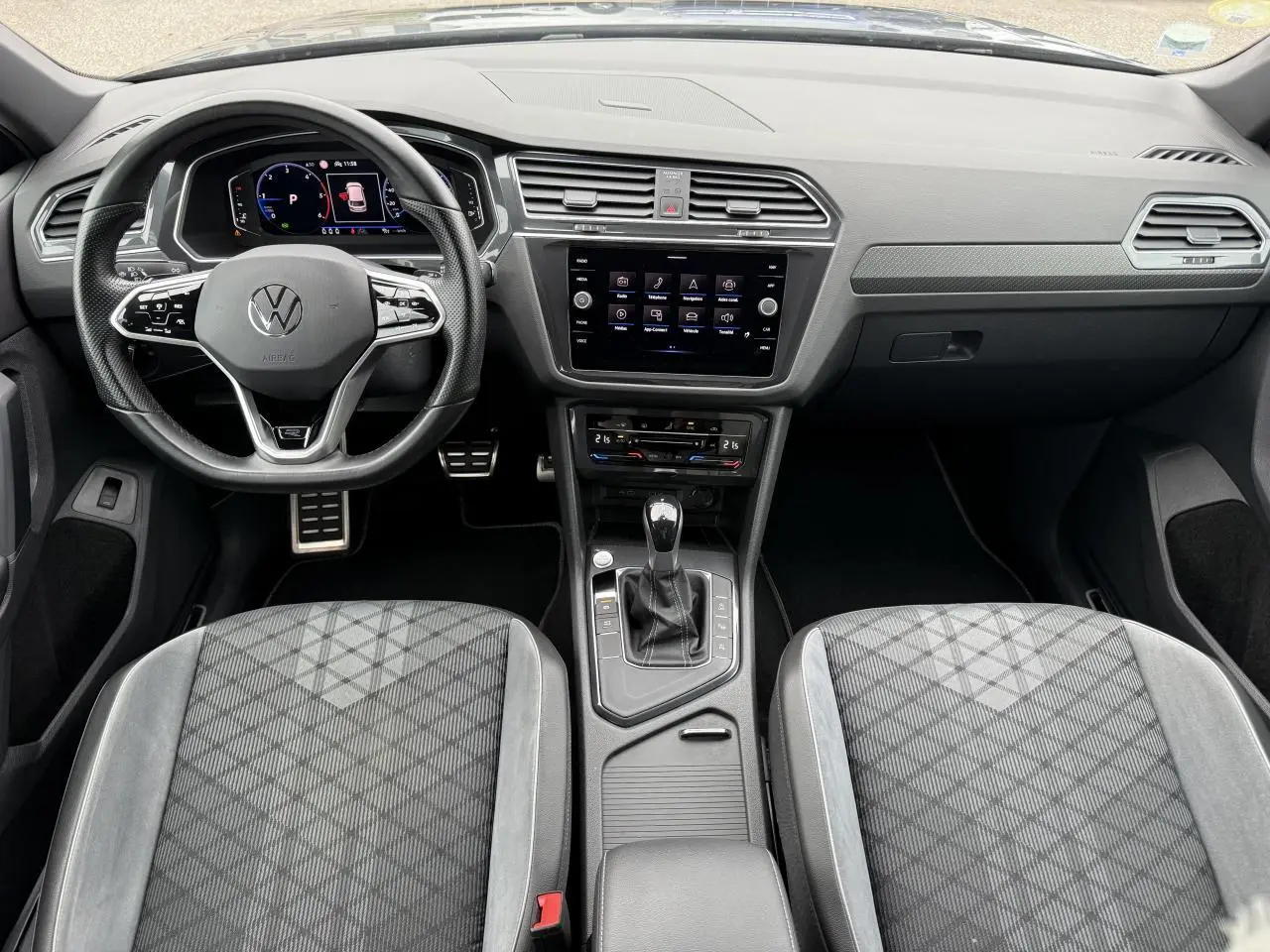 Vue intérieure frontale du Volkswagen Tiguan 2023, volant cuir multifonction et sièges sport en tissu gris.