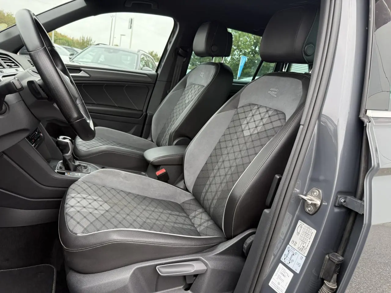 Vue intérieure côté conducteur du Volkswagen Tiguan gris Dauphin 2023, sièges sport en tissu et microfleece avec logo R brodé.