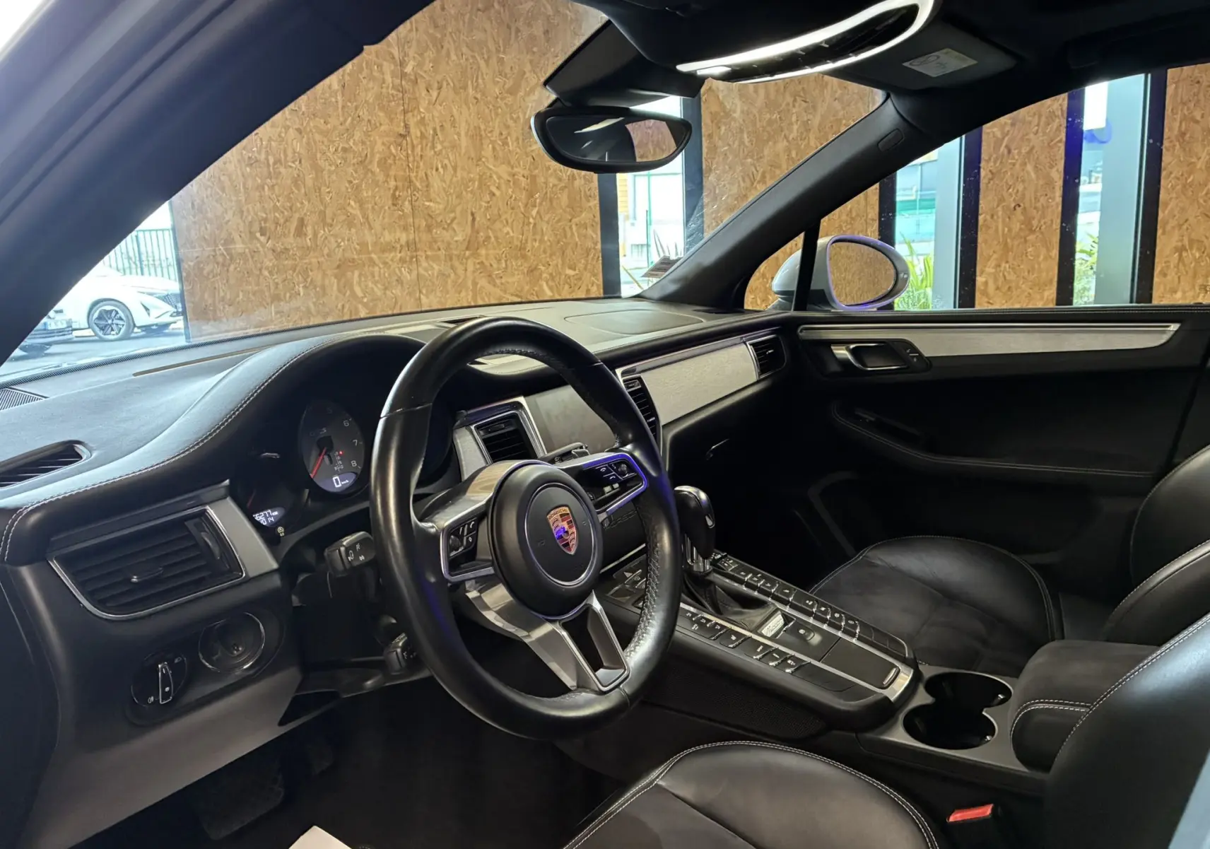Intérieur noir cuir du Porsche Macan GTS 2017, vue côté conducteur sur volant et console centrale avec écran tactile.