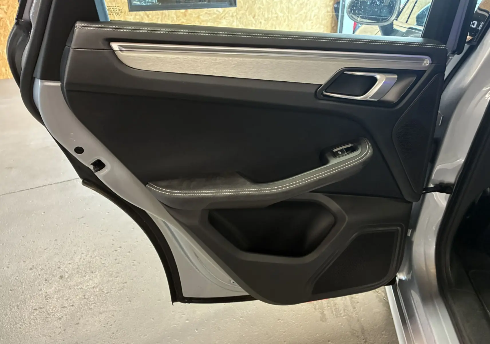 Vue intérieure de la porte arrière gauche grise du Porsche Macan 3.0 360 GTS avec garniture noire et insert aluminium brossé.