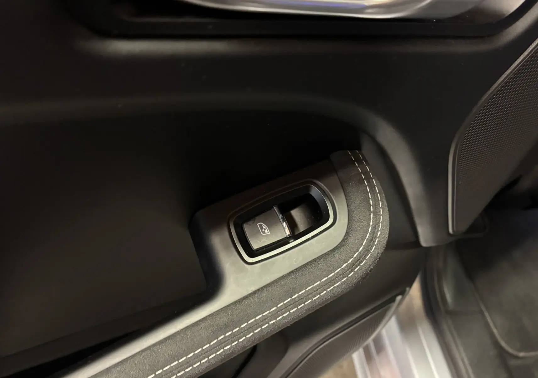 Gros plan sur le bouton de commande de lève-vitre noir avec surpiqûres blanches sur la garniture intérieure du côté conducteur du Porsche Macan GTS 2017.