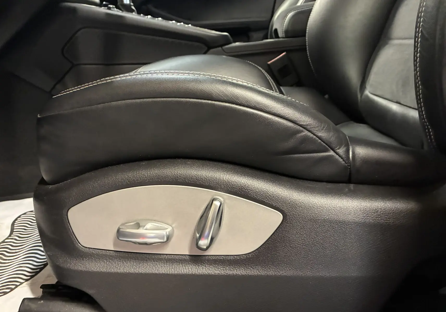 Gros plan sur le côté gauche du siège avant en cuir noir du Porsche Macan GTS 2017 avec commandes électriques intégrées.