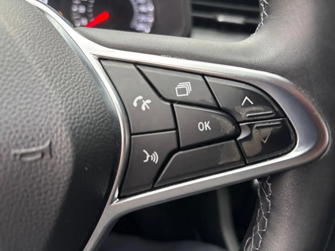 Gros plan sur les commandes multifonctions noires du volant de la Renault Clio gris foncé, version V TCe 90 Equilibre 2022.