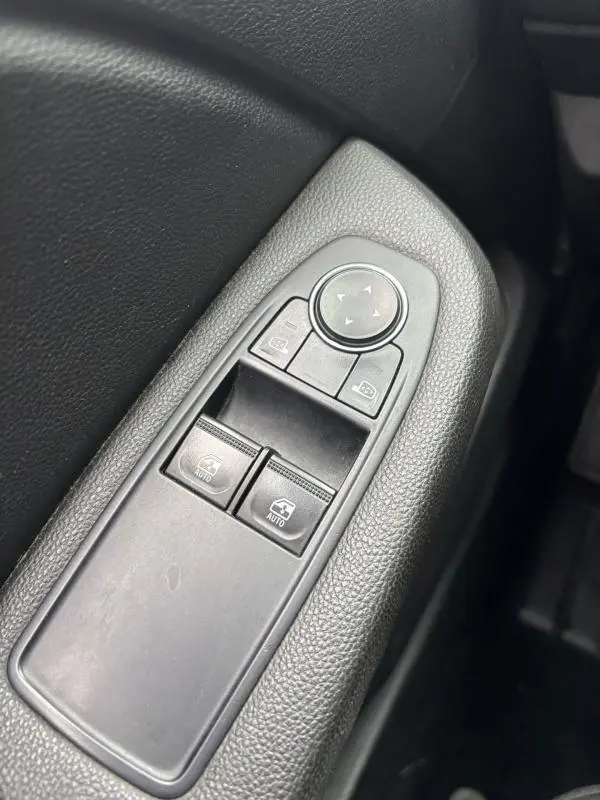 Gros plan sur les commandes de lève-vitres et réglage des rétroviseurs côté conducteur d'une Renault Clio gris foncé 2022.