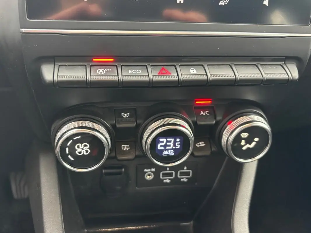 Gros plan sur la console centrale de la Renault Clio V TCe 90, avec commandes de climatisation et boutons fonctionnels.