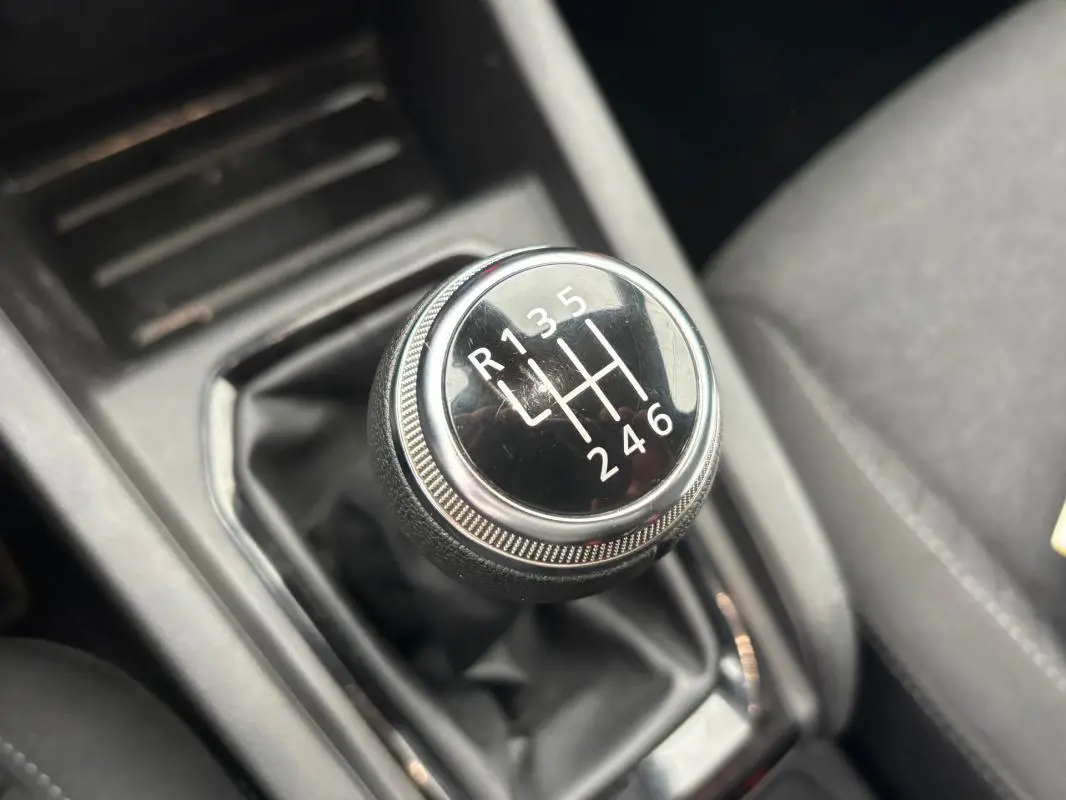 Gros plan sur le levier de vitesses manuel noir de la Renault Clio gris foncé, avec marquage des six rapports et marche arrière.