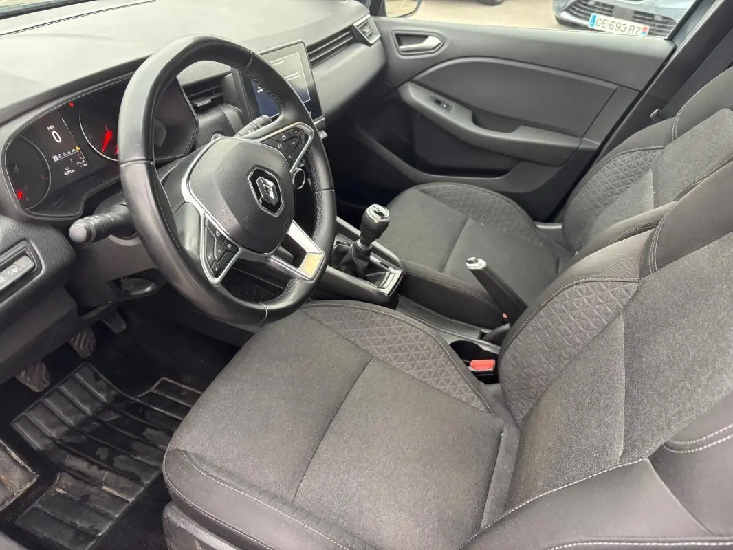 Intérieur de Renault Clio V TCe 90 Equilibre 2022, vue côté conducteur montrant volant, sièges gris foncé et levier de vitesse manuel.