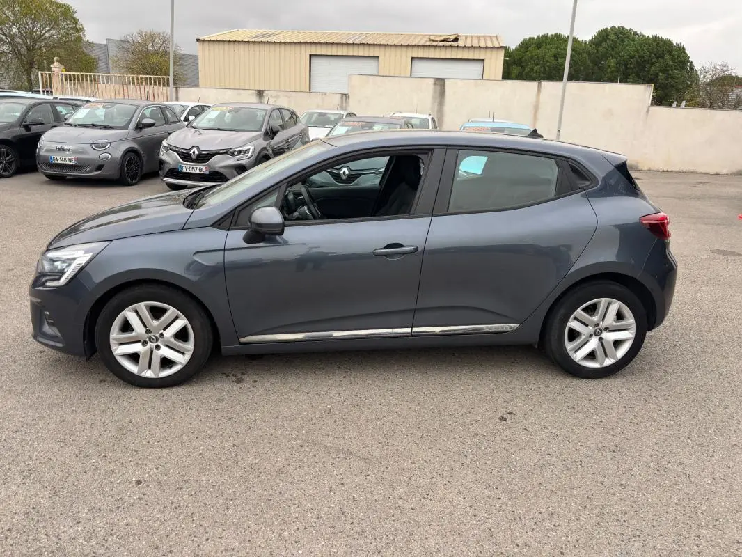 Profil côté gauche d'une Renault Clio gris foncé 2022, finition V TCe 90 Equilibre, sur parking extérieur.