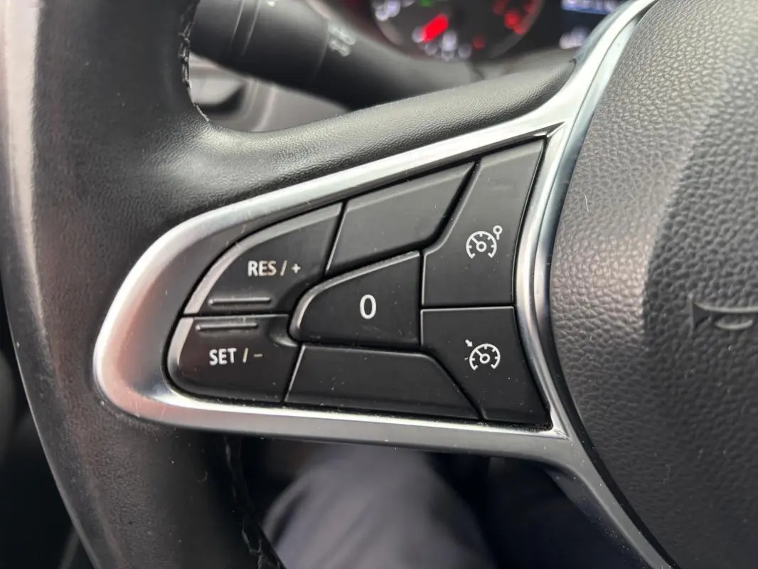 Gros plan sur les commandes du régulateur de vitesse au volant d'une Renault Clio gris foncé 2022.
