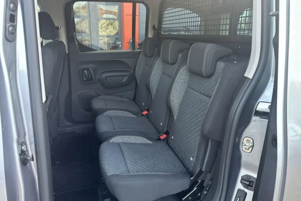 Vue intérieure côté droit des sièges arrière en tissu gris du Peugeot Rifter BlueHDi 130 Allure avec grille de séparation dans le coffre.