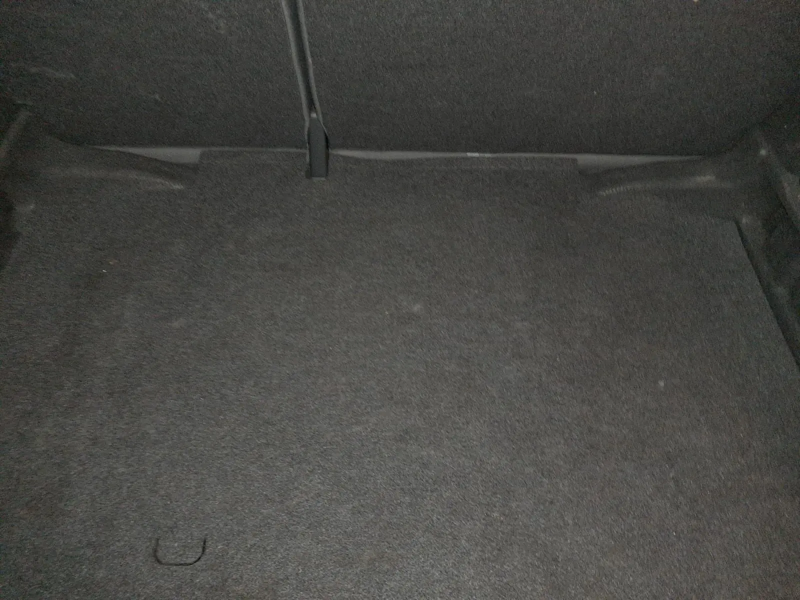 Coffre vide de l'Audi A1 Sportback noir, vue intérieure montrant le revêtement de sol en tissu gris foncé.