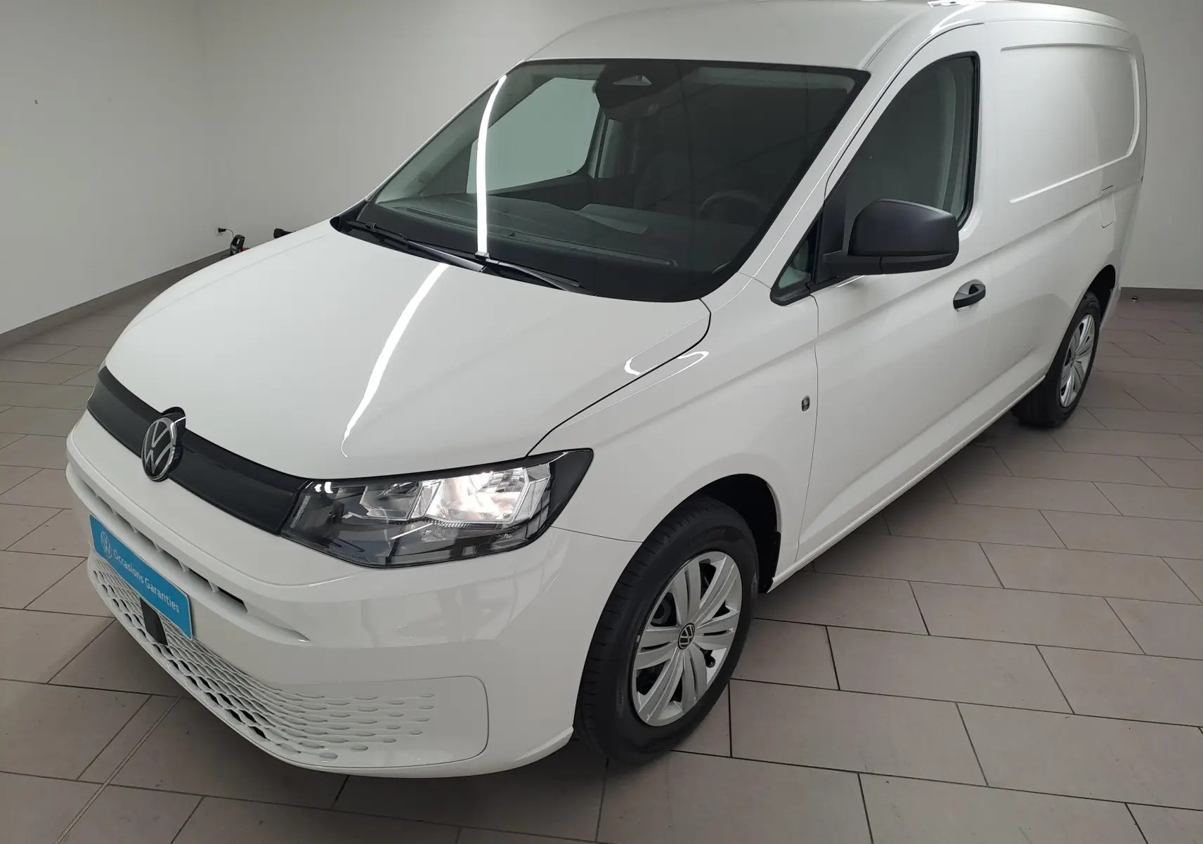 Vue 3/4 avant droite du Volkswagen Caddy Cargo Maxi blanc Candy 2026 avec calandre noire et jantes acier.