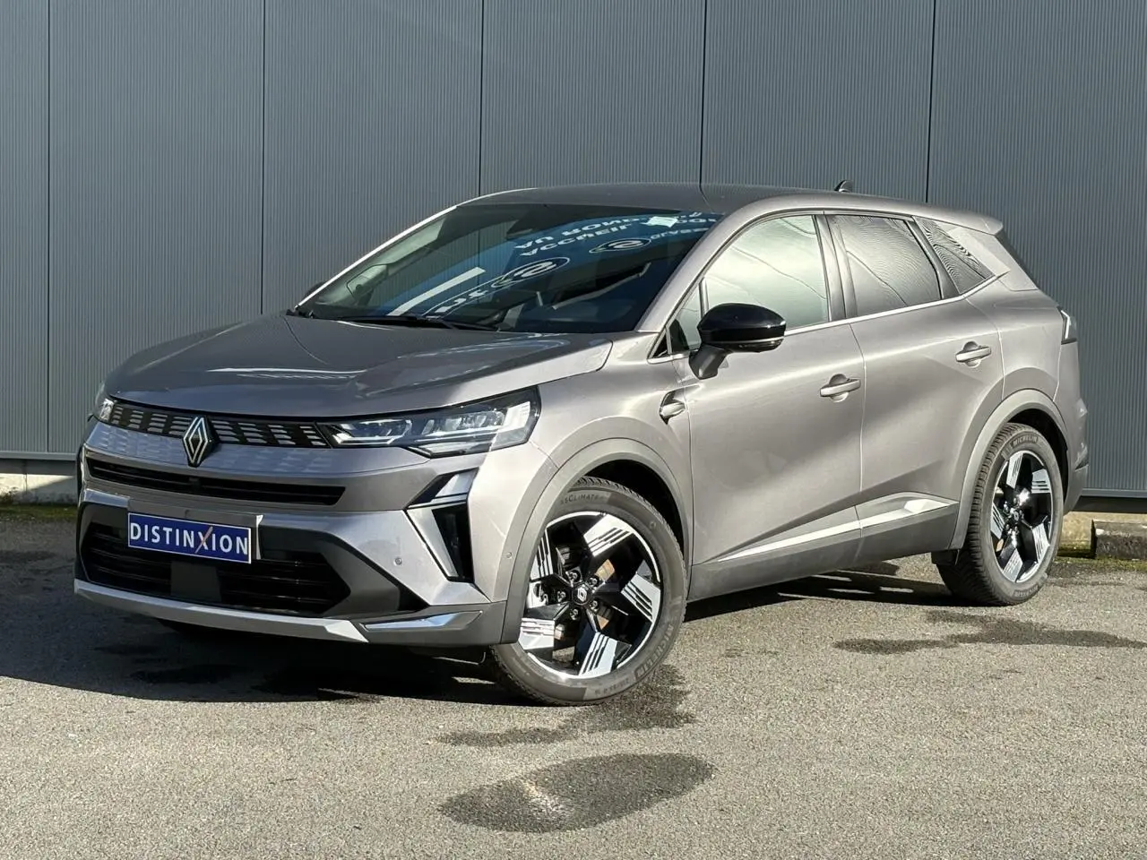 Renault Symbioz gris Cassiopée en 3/4 avant droit, avec jantes 18 pouces et calandre moderne noire.