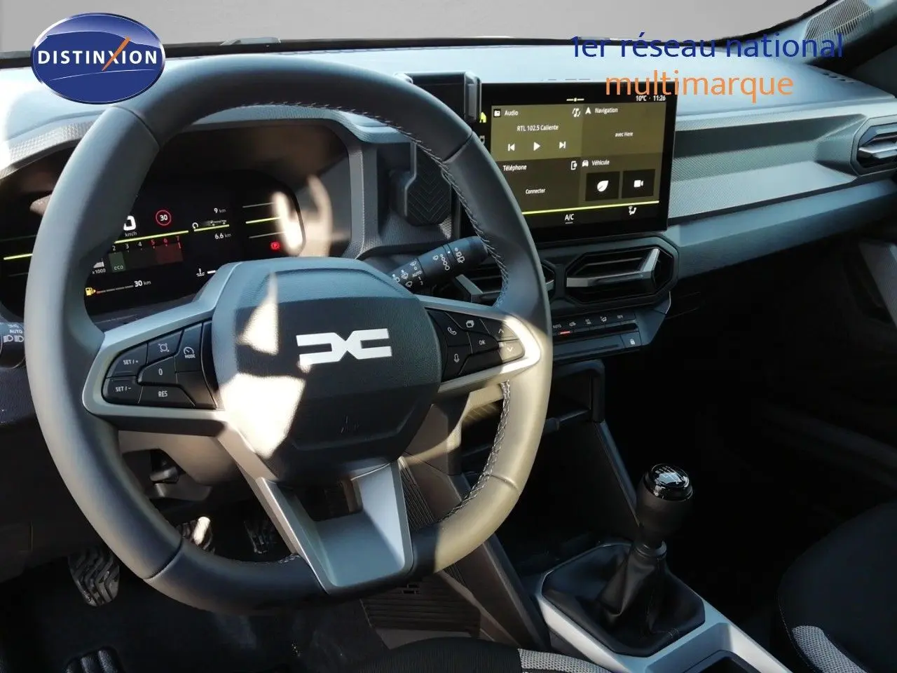Vue intérieure du tableau de bord du Dacia Duster 2026 avec volant multifonction, écran tactile et levier de vitesse manuel.