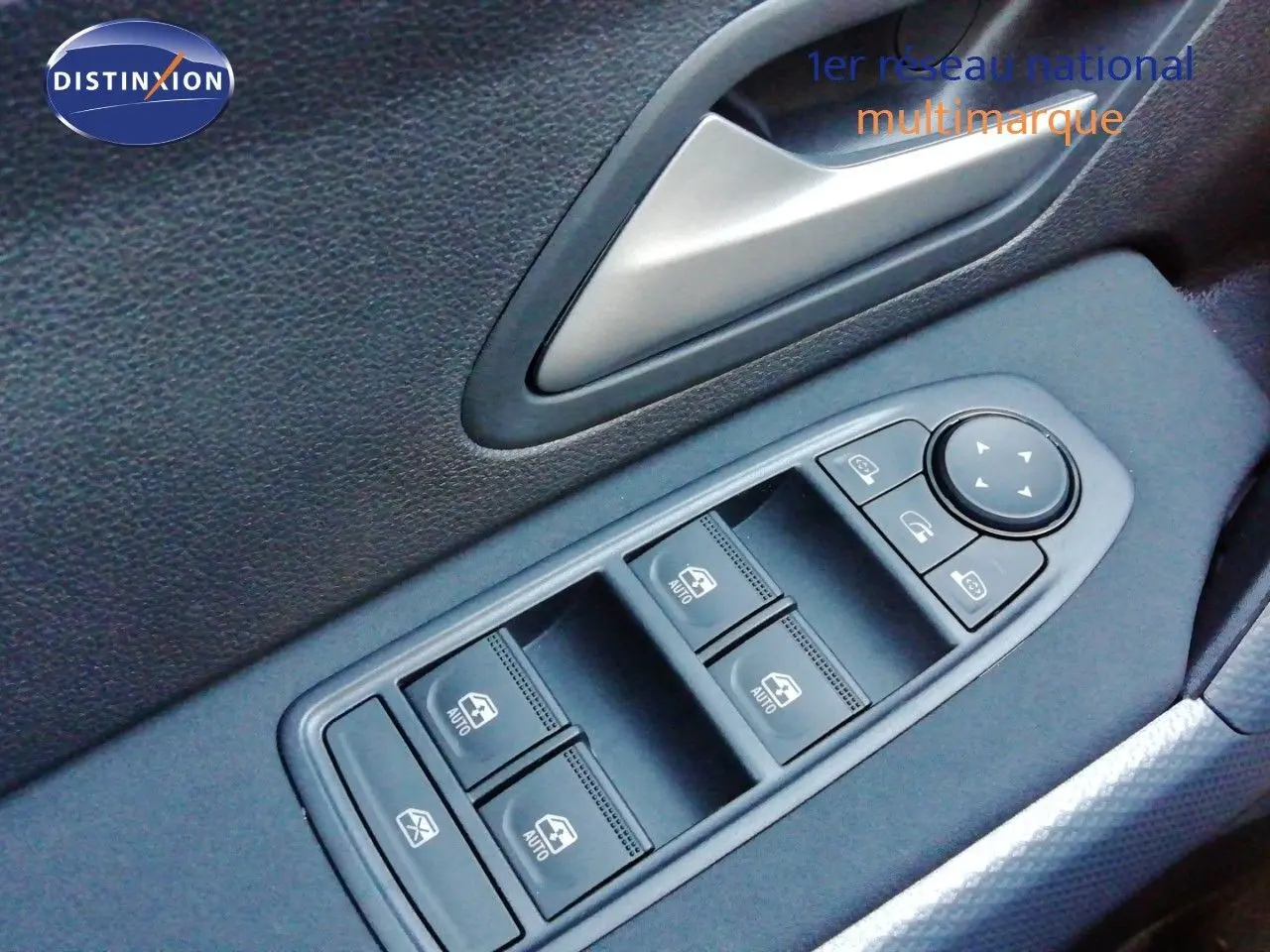 Gros plan sur les commandes des vitres électriques et rétroviseurs sur la porte côté conducteur d'un Dacia Duster gris schiste métal.