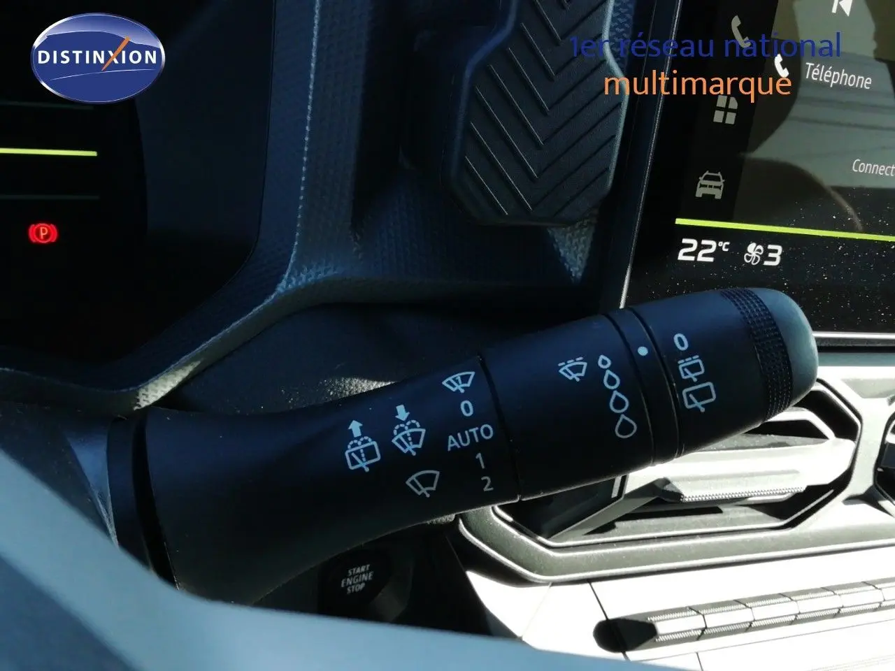 Gros plan sur la manette des essuie-glaces du Dacia Duster 2026 gris schiste, avec tableau de bord et écran tactile en arrière-plan.