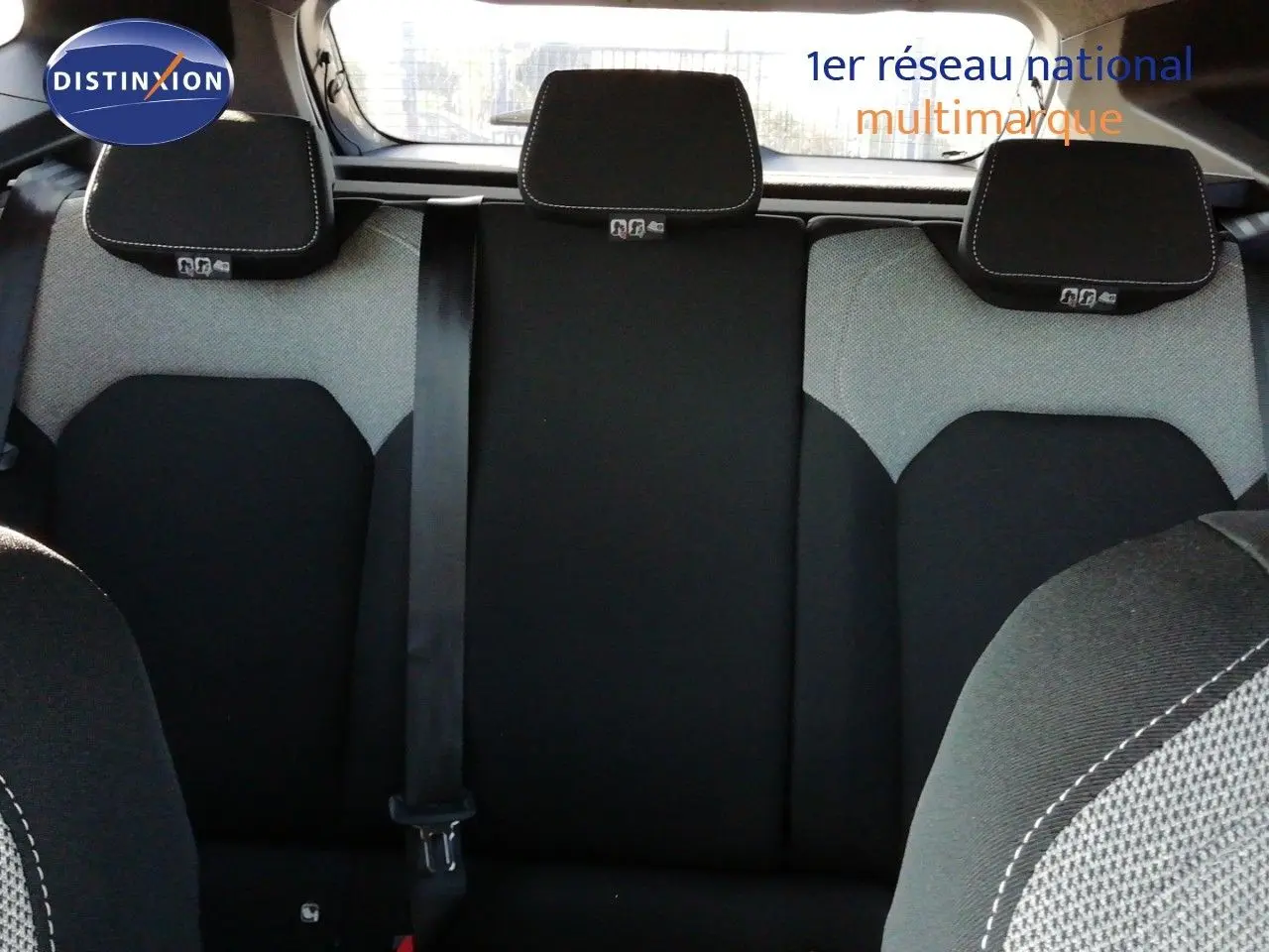 Vue intérieure arrière du Dacia Duster 2026, sièges en tissu gris et noir avec appuie-têtes et ceinture de sécurité visible.