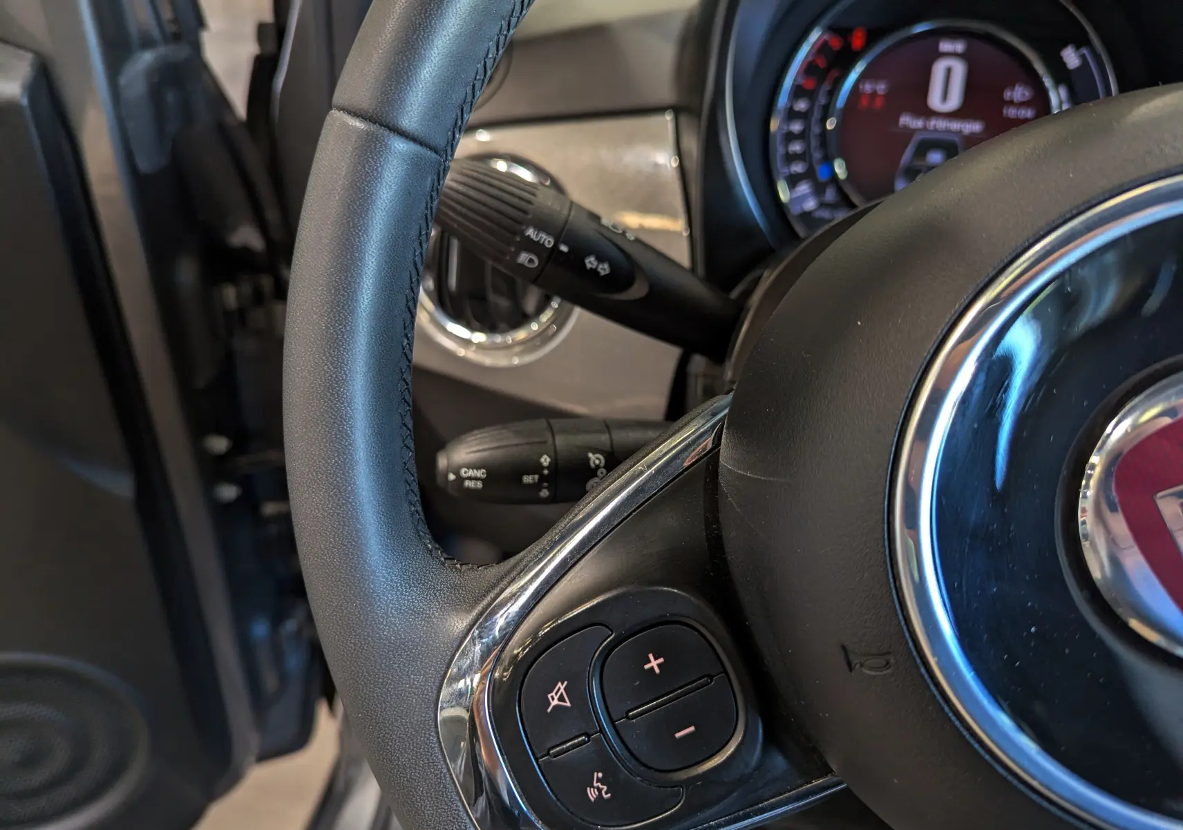 Gros plan sur le volant en cuir noir du Fiat 500 Electroclash Grey, avec commandes audio intégrées visibles.