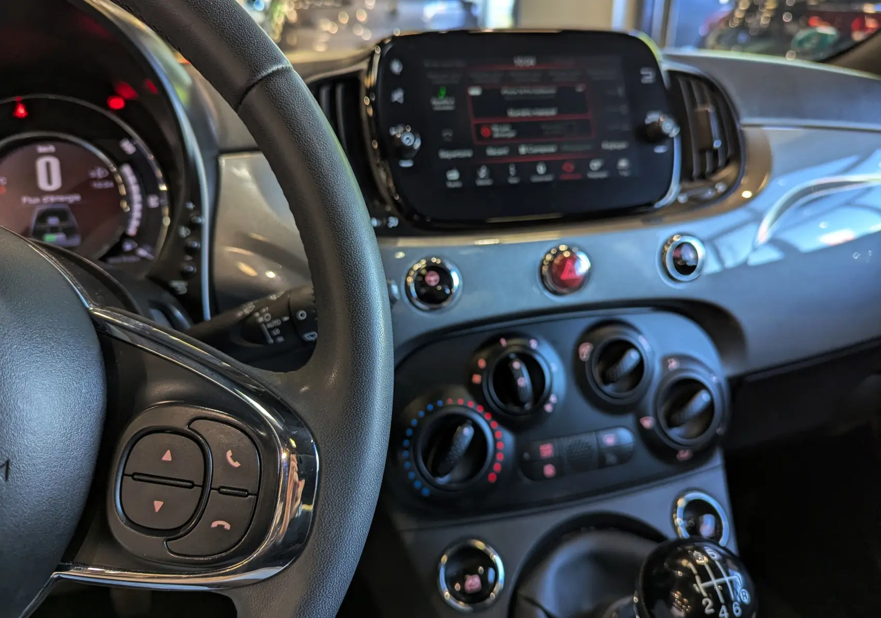 Vue rapprochée de l’intérieur côté conducteur de la Fiat 500 hybride 2021, avec tableau de bord gris Electroclash et levier de vitesses manuel.