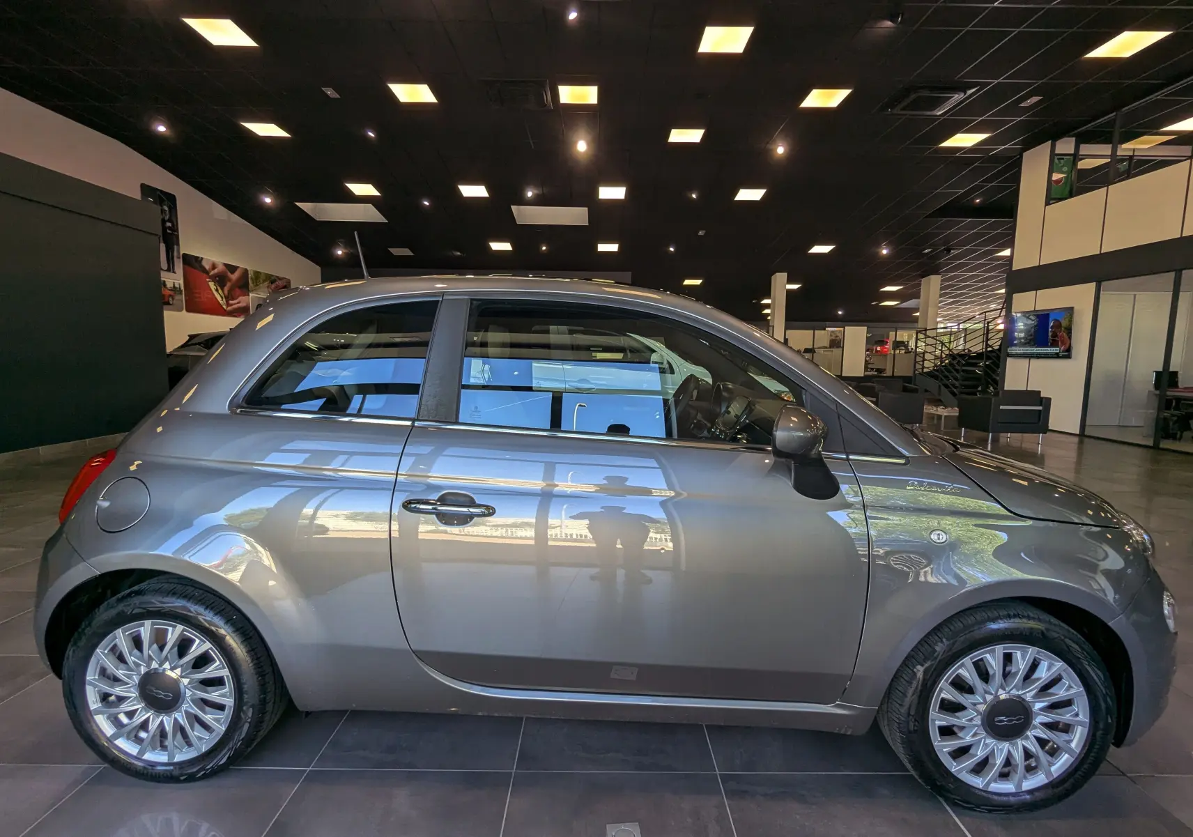 Profil droit d'une FIAT 500 hybride 2021 en Electroclash Grey, avec jantes alliage et finition DolceVita visible en concession.