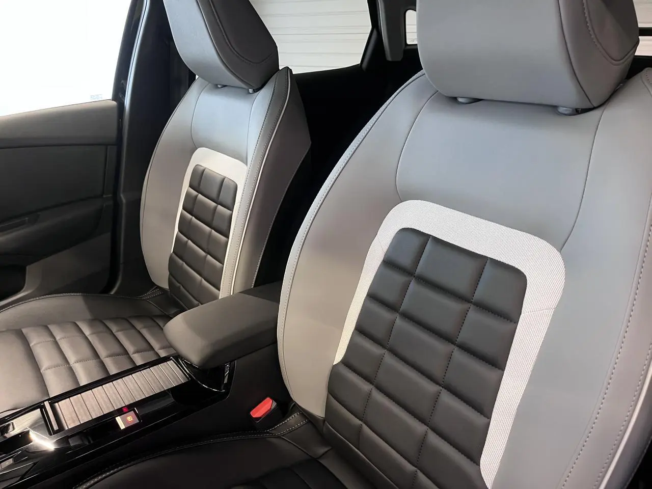 Gros plan sur les sièges avant bicolores noir et gris clair de la Citroën C4 2025 avec accoudoir central.