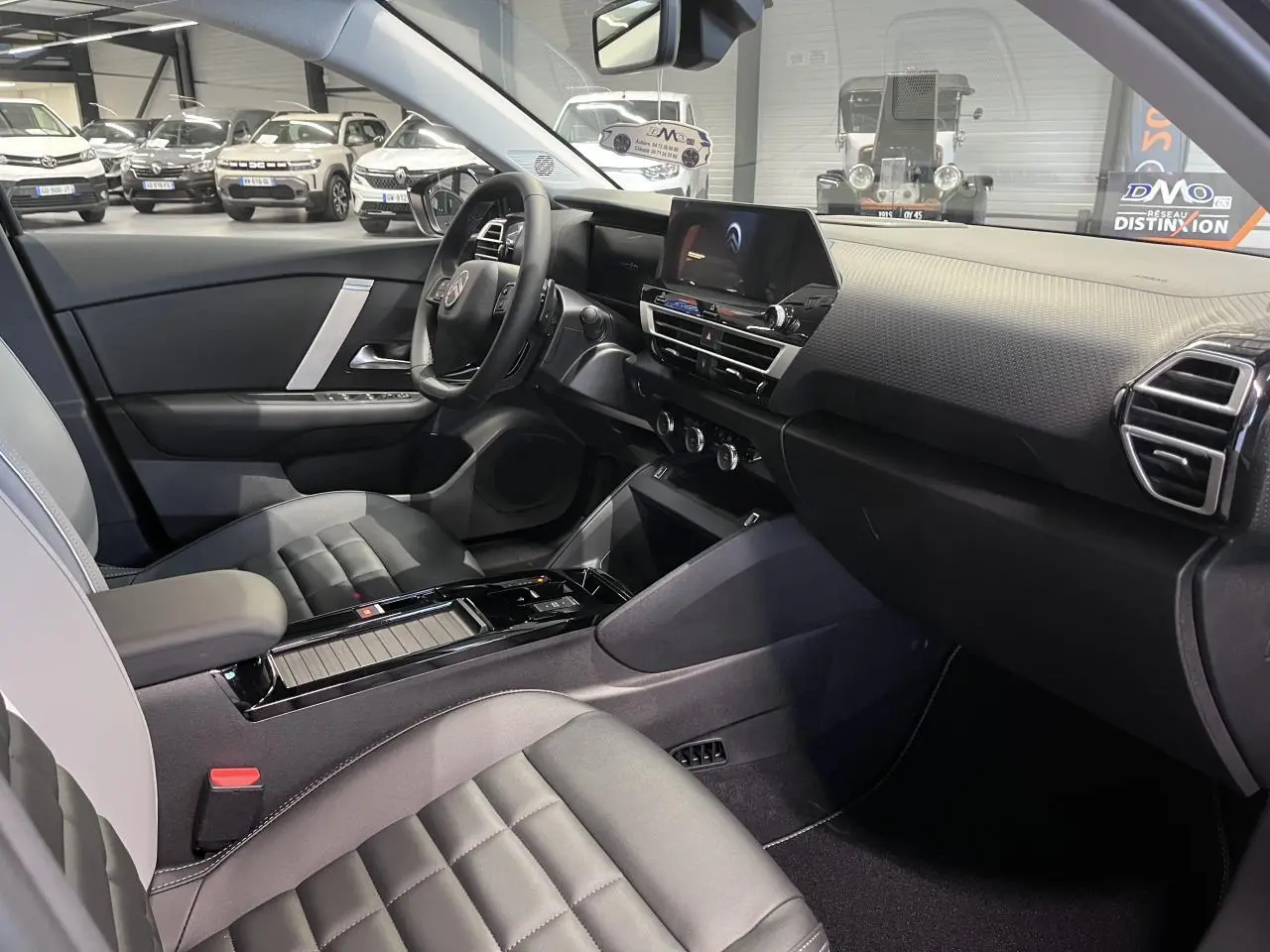 Intérieur avant droit de la Citroën C4 2025 hybride, sièges Advanced Comfort noirs et tableau de bord moderne.