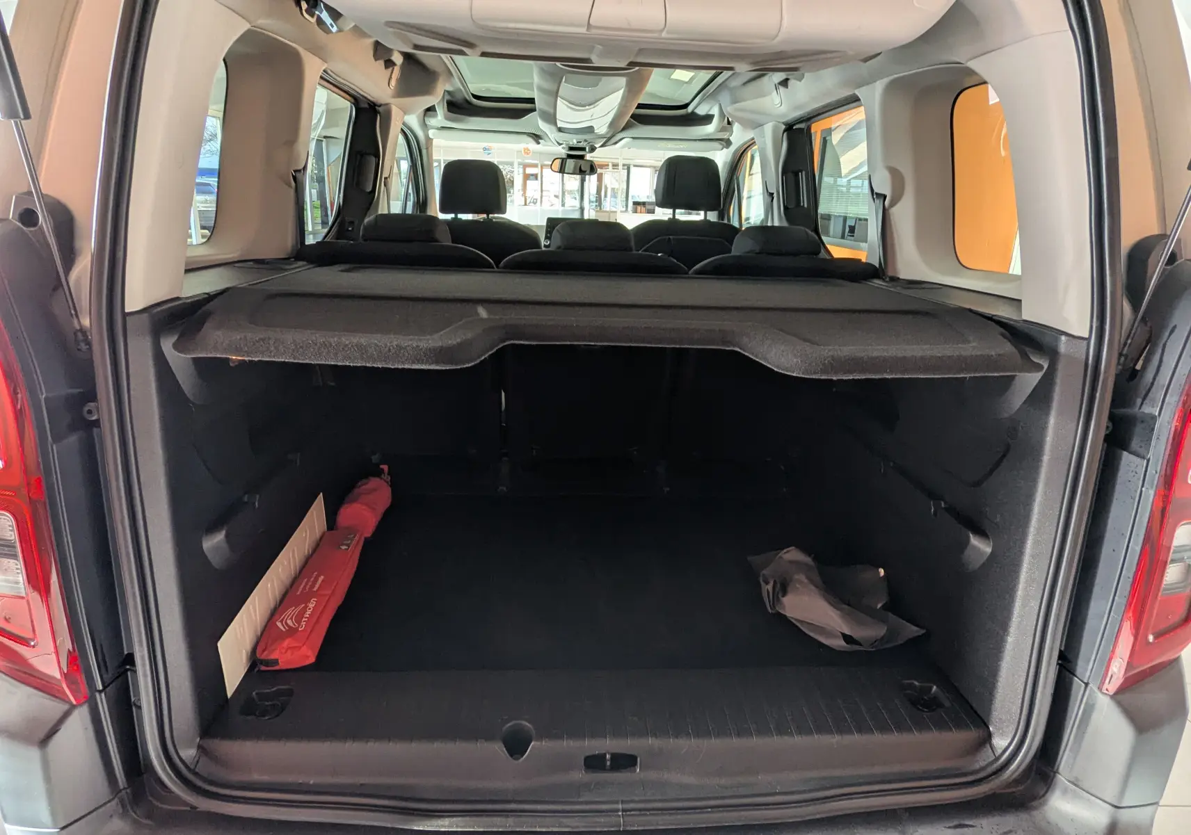 Vue arrière du Citroën Berlingo beige 2019, coffre ouvert avec cache-bagages et sièges arrière visibles.