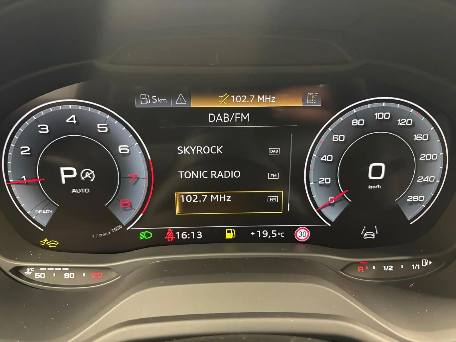 Tableau de bord numérique de l'Audi Q2 35 TFSI 2026 affichant la radio DAB/FM et compte-tours à l'arrêt.