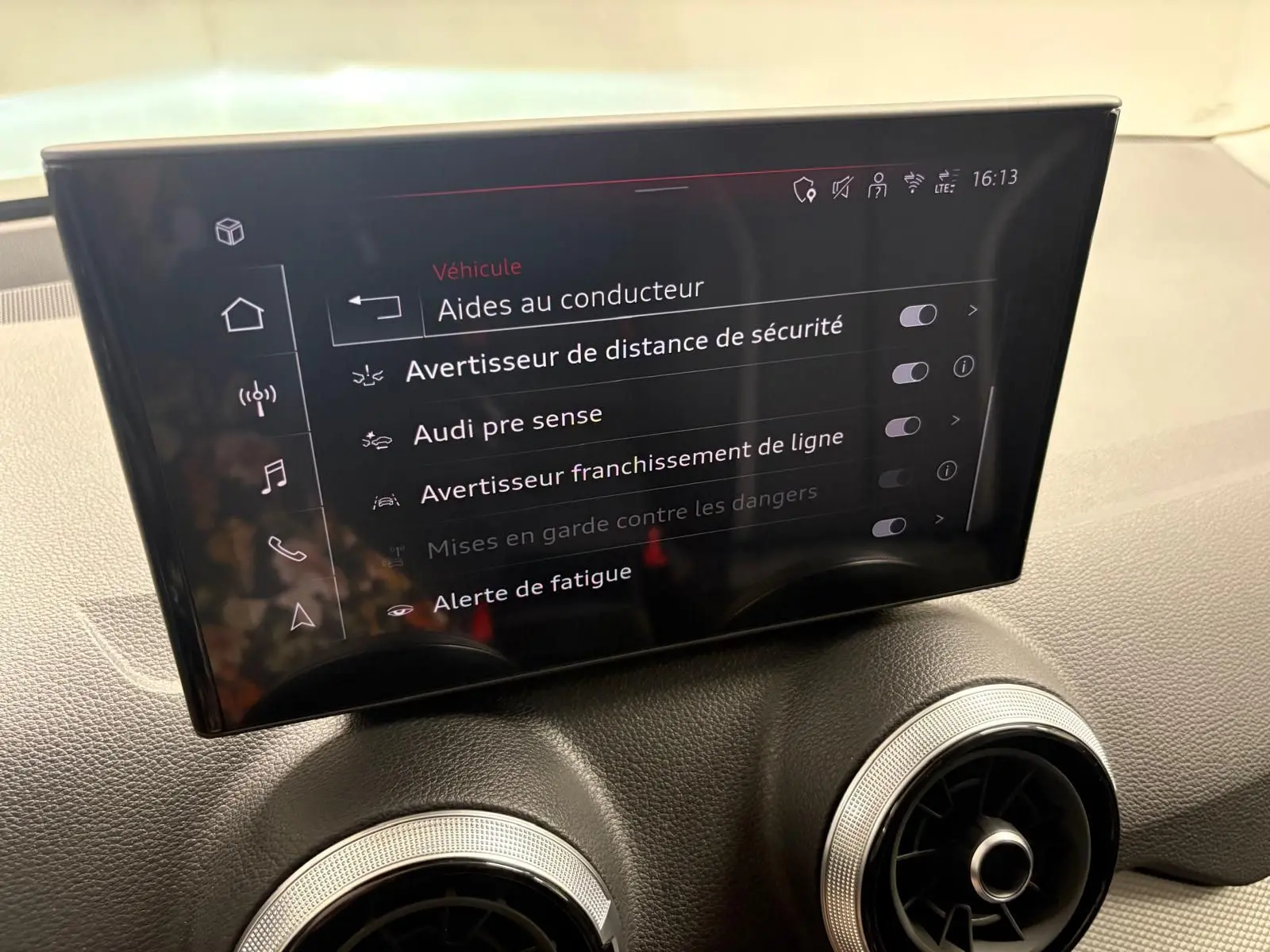 Écran central intérieur de l’Audi Q2 35 TFSI S Line 2026 affichant les aides à la conduite, avec tableau de bord gris.