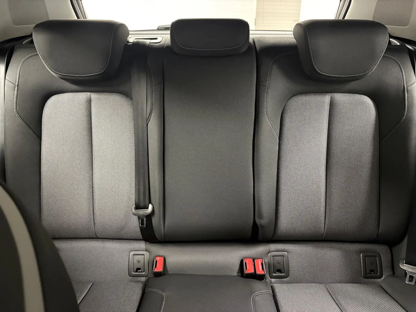Vue arrière intérieure des sièges arrière noirs de l'Audi Q2 35 TFSI S Line 2026 avec appuie-têtes et ceintures visibles.