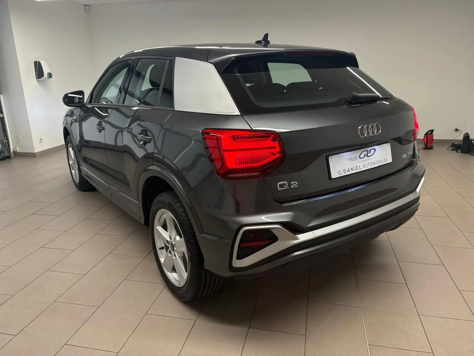 Vue 3/4 arrière droite de l'Audi Q2 35 TFSI S Line gris Daytona avec toit noir et montant arrière argenté.
