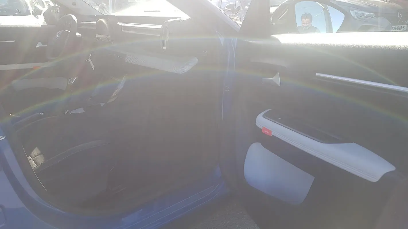 Vue intérieure côté passager d'une Citroën C3 bleu foncé 2024 avec détails du panneau de porte clair et volant visible.