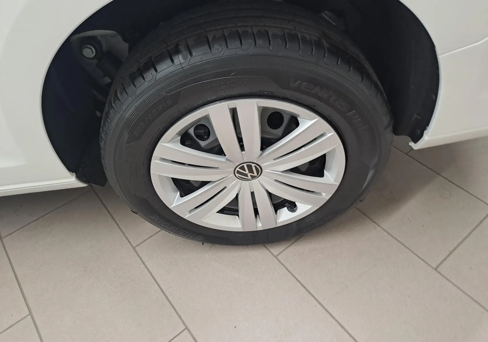 Gros plan sur la roue avant gauche blanche du Volkswagen Caddy Cargo Maxi 2026 avec jante argentée et pneu noir.