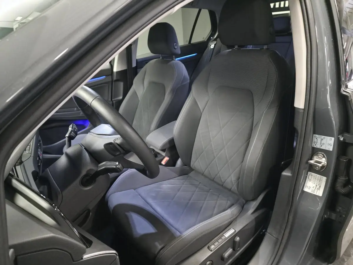 Vue intérieure côté conducteur de la Volkswagen Golf gris avec sièges sport confort et éclairage d'ambiance bleu.
