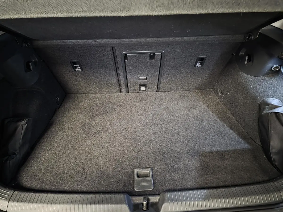 Coffre spacieux et propre de la Volkswagen Golf 1.4 eHybrid gris, vue intérieure arrière avec tapis gris.