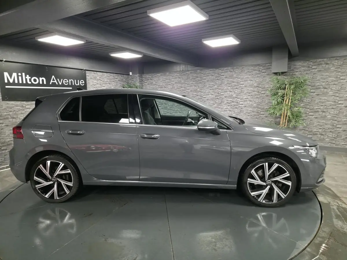 Volkswagen Golf 8 hybride rechargeable gris vue de profil côté gauche avec jantes alliage 18 pouces en intérieur showroom.