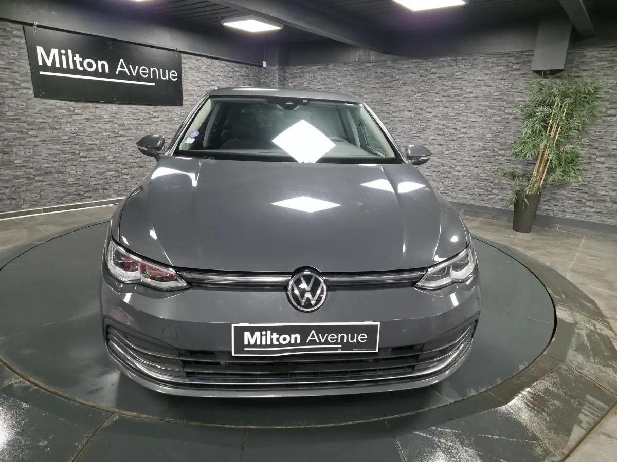 Volkswagen Golf 1.4 eHybrid gris vue de face en intérieur avec logo VW et plaque Milton Avenue visible