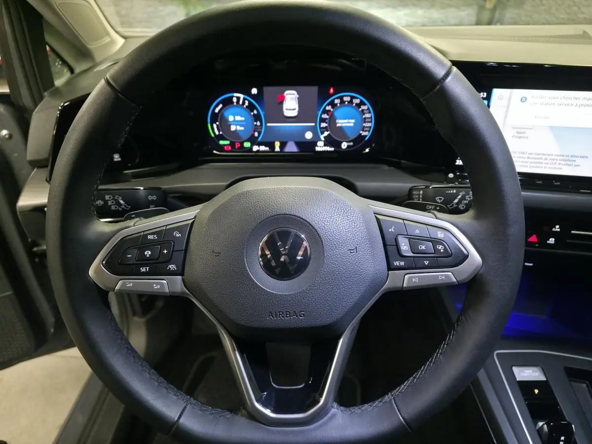 Vue intérieure centrée sur le volant noir de la Volkswagen Golf 1.4 eHybrid 2020 avec tableau de bord digital lumineux.